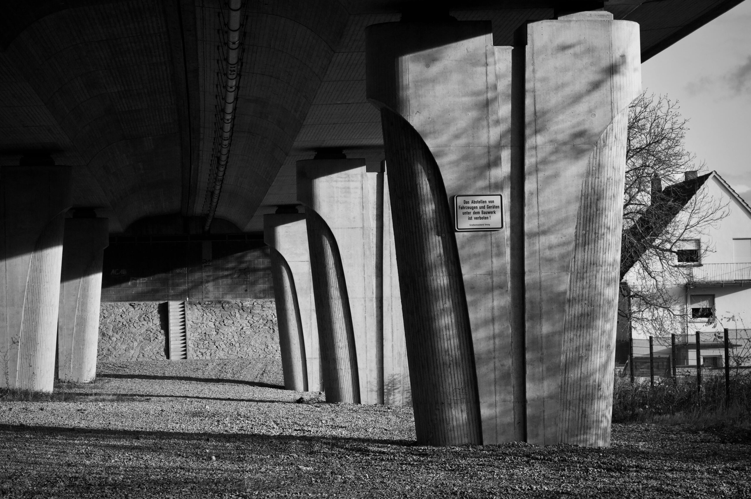 Schwarzwei&szlig;es Foto einer modernen Betonunterf&uuml;hrung mit dramatischen Schatten und strukturierter Gestaltung.